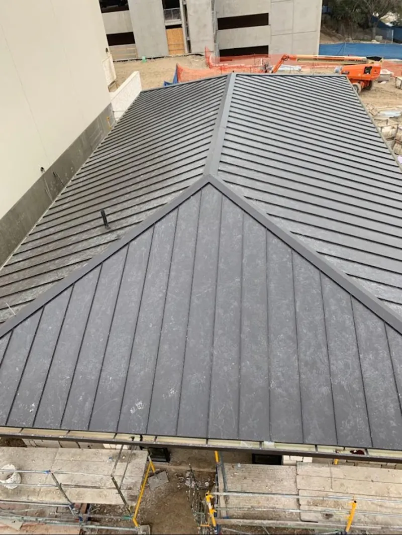 Commercial metal roof construction with crane equipment in Hewitt